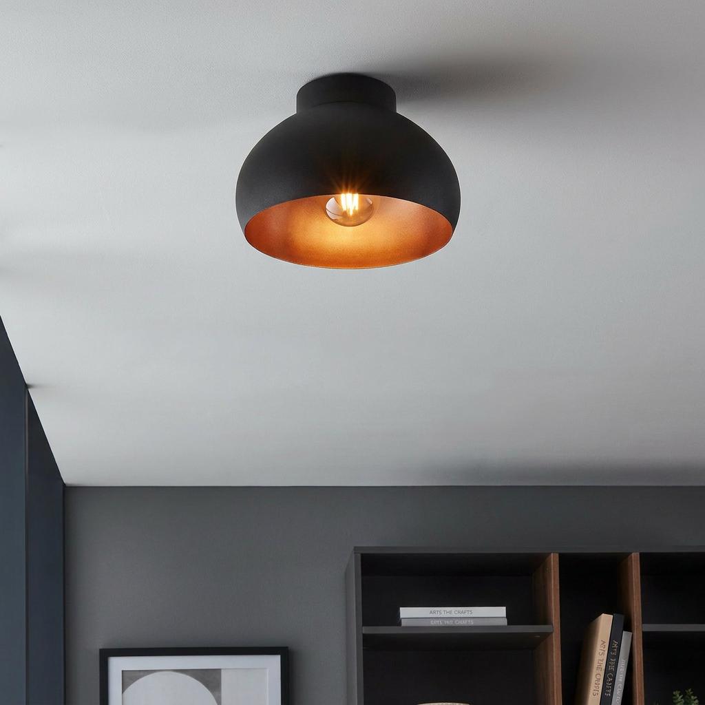 Black flush ceiling light with a copper interior illuminating a modern room.