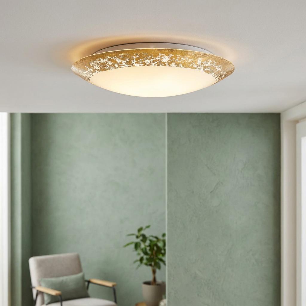 Round LED flush ceiling light with a gold leaf style rim illuminating a modern room with green walls.