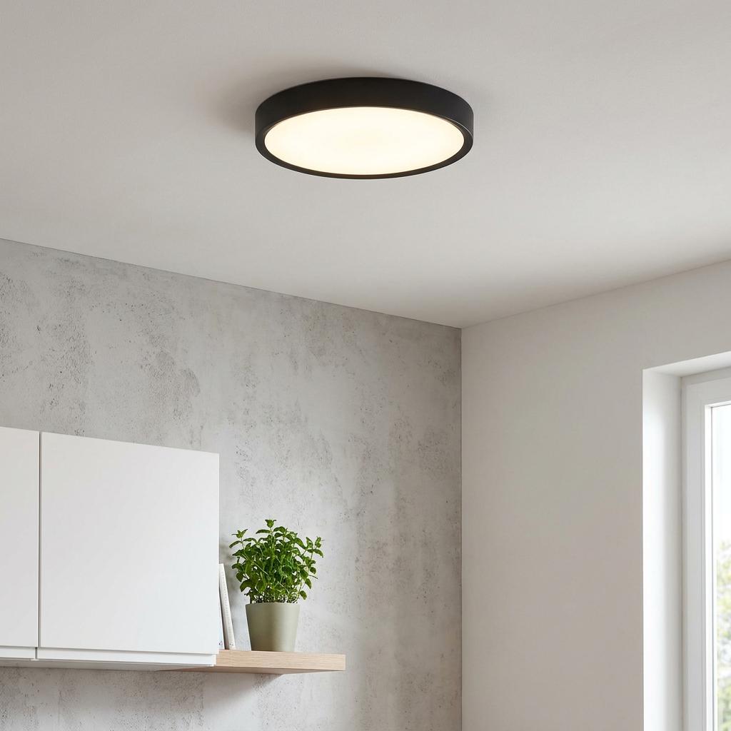 Illuminated Eglo Musurita round black LED flush light on a white ceiling above a modern kitchen shelf.