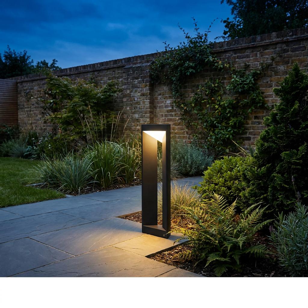 Black linear LED bollard light illuminating a stone garden path next to a brick wall at night.