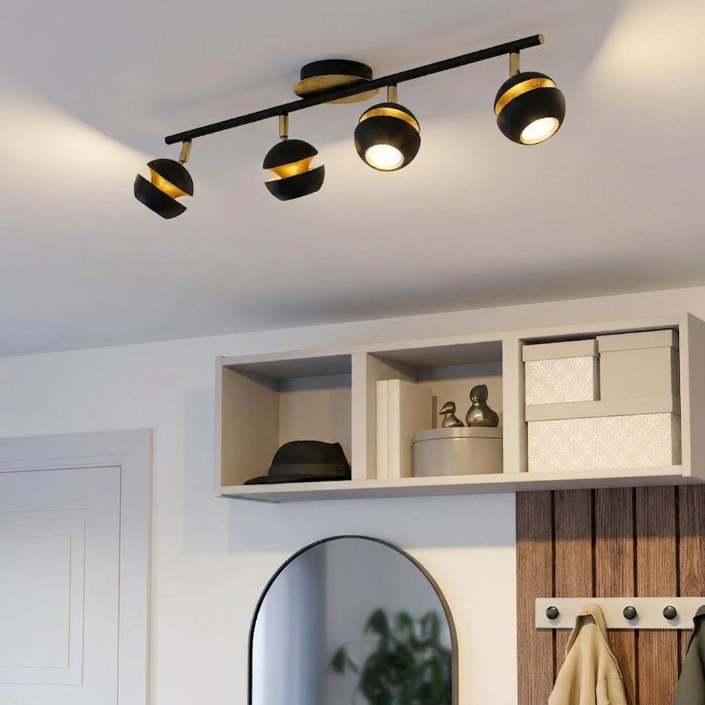 Modern black and gold four-light bar spotlight illuminating a contemporary hallway with shelving and a mirror.