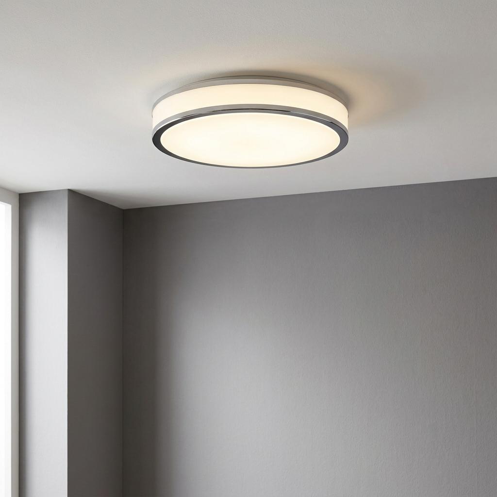 Modern round chrome LED flush ceiling light with a white diffuser illuminating a gray room.