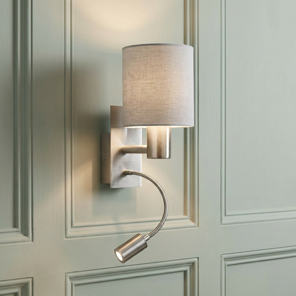 Satin nickel wall light with a taupe shade and adjustable LED reading arm mounted on a green paneled wall.
