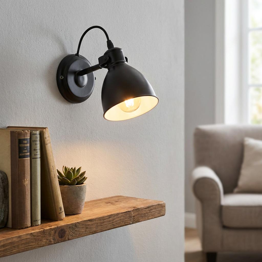 Eglo Priddy black wall spotlight illuminating a rustic wooden shelf with books and a succulent plant.