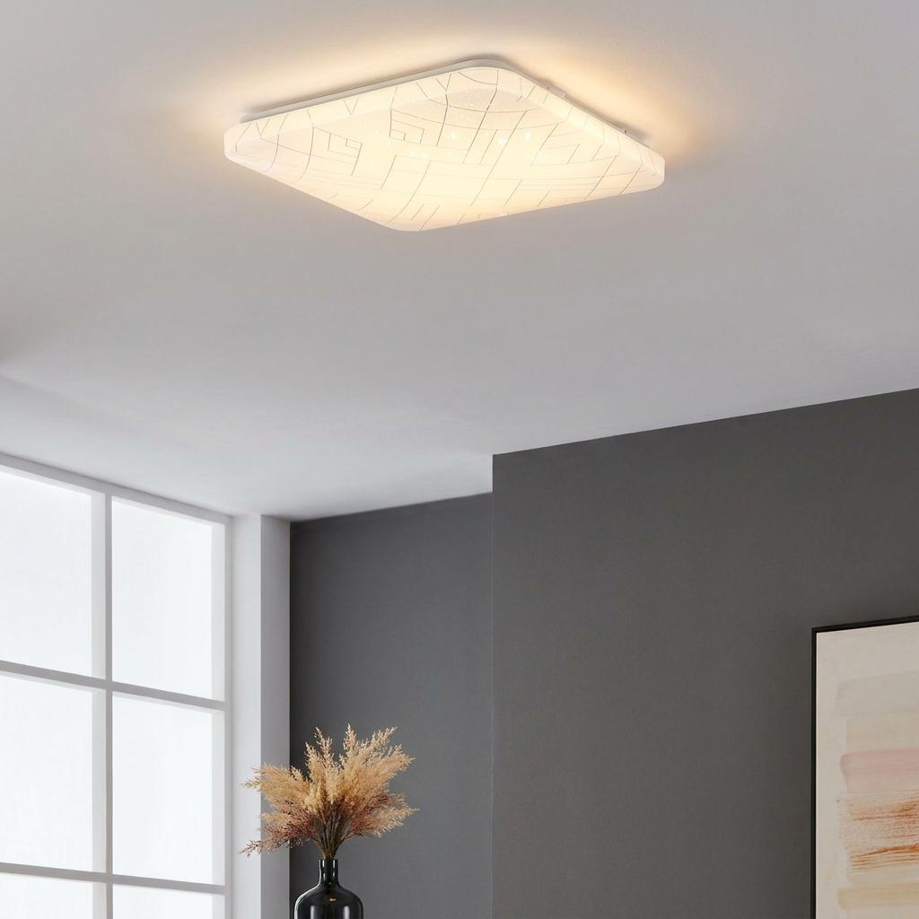 Square flush mount ceiling light with a patterned white shade illuminated in a modern grey room.