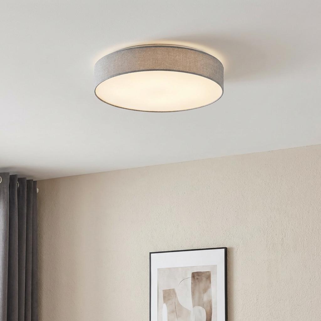 Modern grey linen drum flush mount ceiling light illuminating a neutral living space.