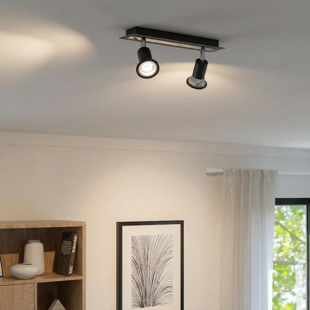Eglo Sarria black and chrome two-light bar spotlight mounted on a white ceiling in a modern living room.