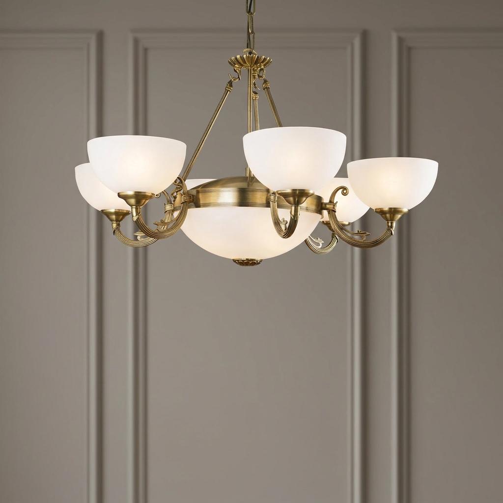 Six-light bronze chandelier with white glass shades hanging against a grey paneled wall.