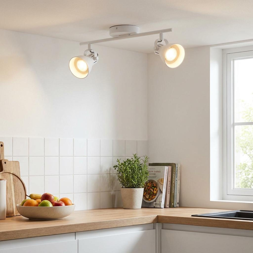 White 2-light bar spotlight fixture illuminated on a kitchen ceiling above a wooden countertop.