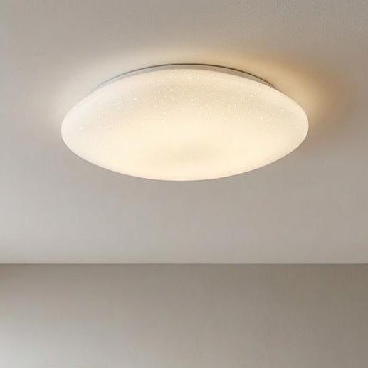 Round Eglo Sileras sparkling effect LED flush ceiling light illuminated in a minimalist room with beige walls.