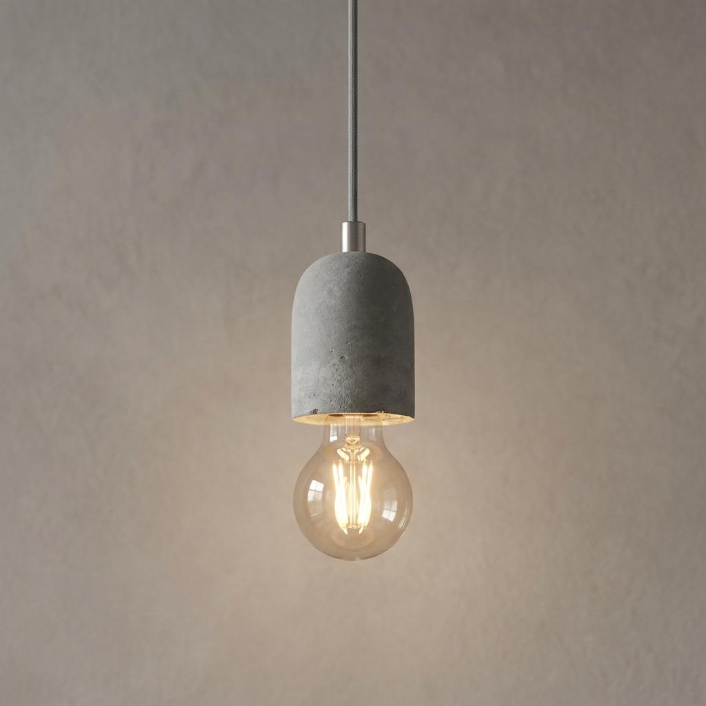Concrete pendant light with a glowing filament bulb suspended against a neutral textured wall.