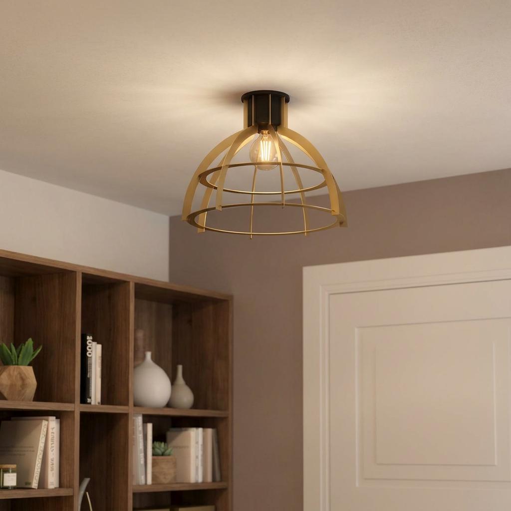 Industrial gold cage flush ceiling light with a black base, illuminated in a room with a wooden bookshelf.