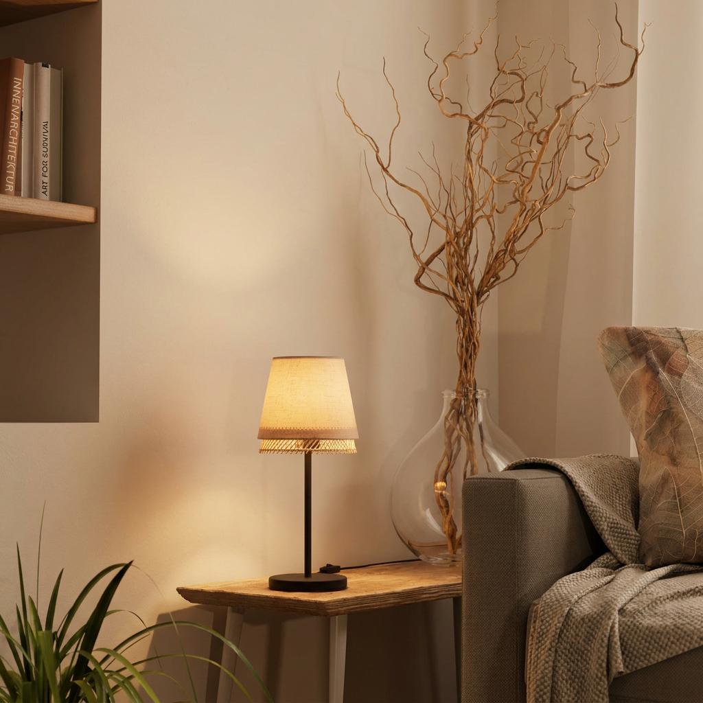 Black metal table lamp with a fabric and wood lattice shade on a wooden console table in a warm living room.