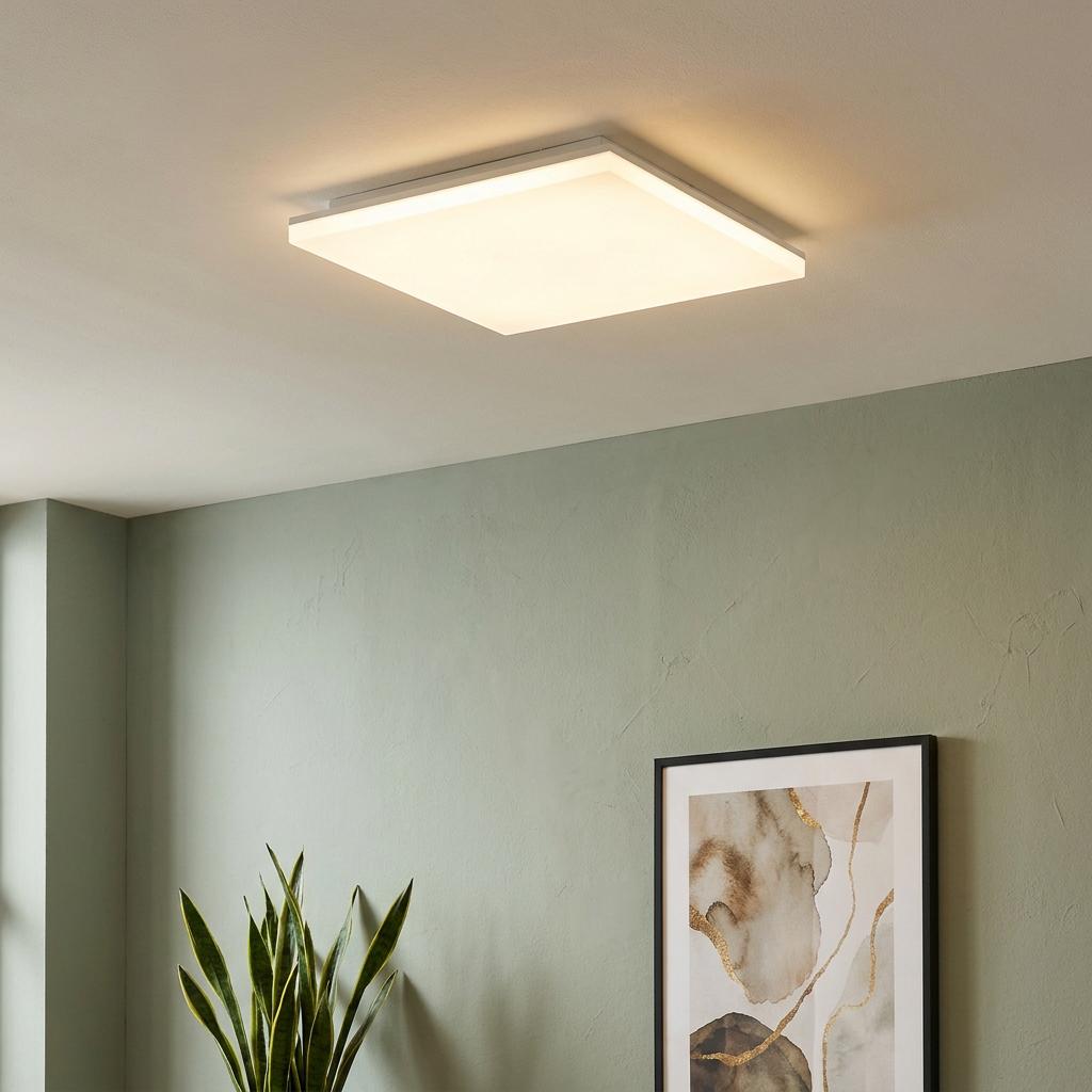 Square white LED flush ceiling light illuminating a room with sage green walls and minimalist decor.