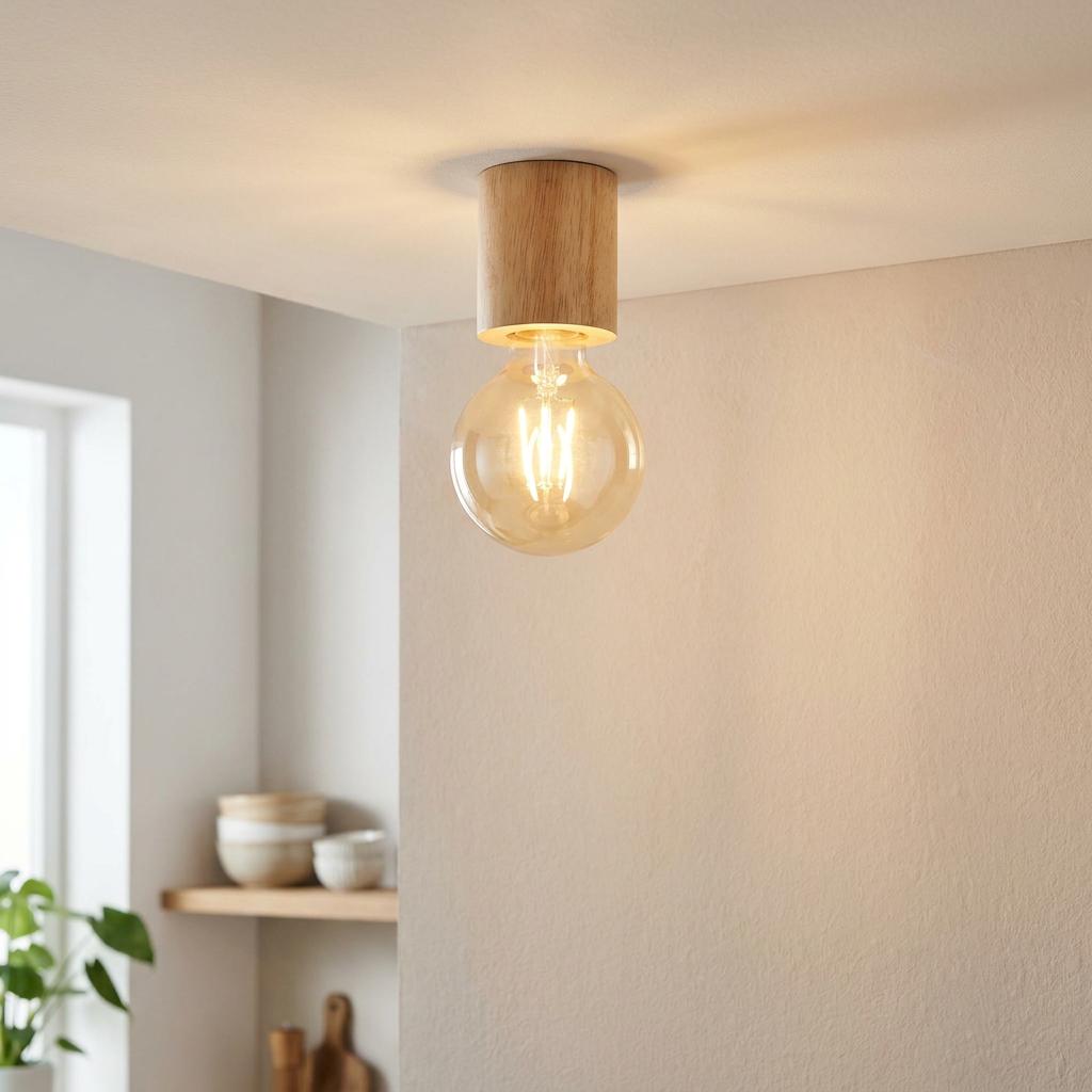 Minimalist light wood cylindrical ceiling light with a large glowing amber bulb in a modern home.