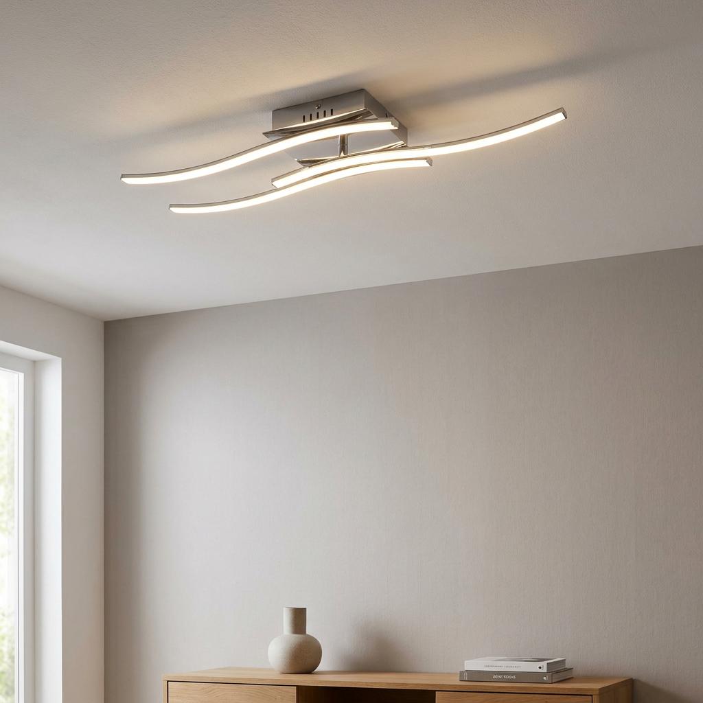Modern chrome flush ceiling light with wavy LED bars mounted in a minimalist living room.