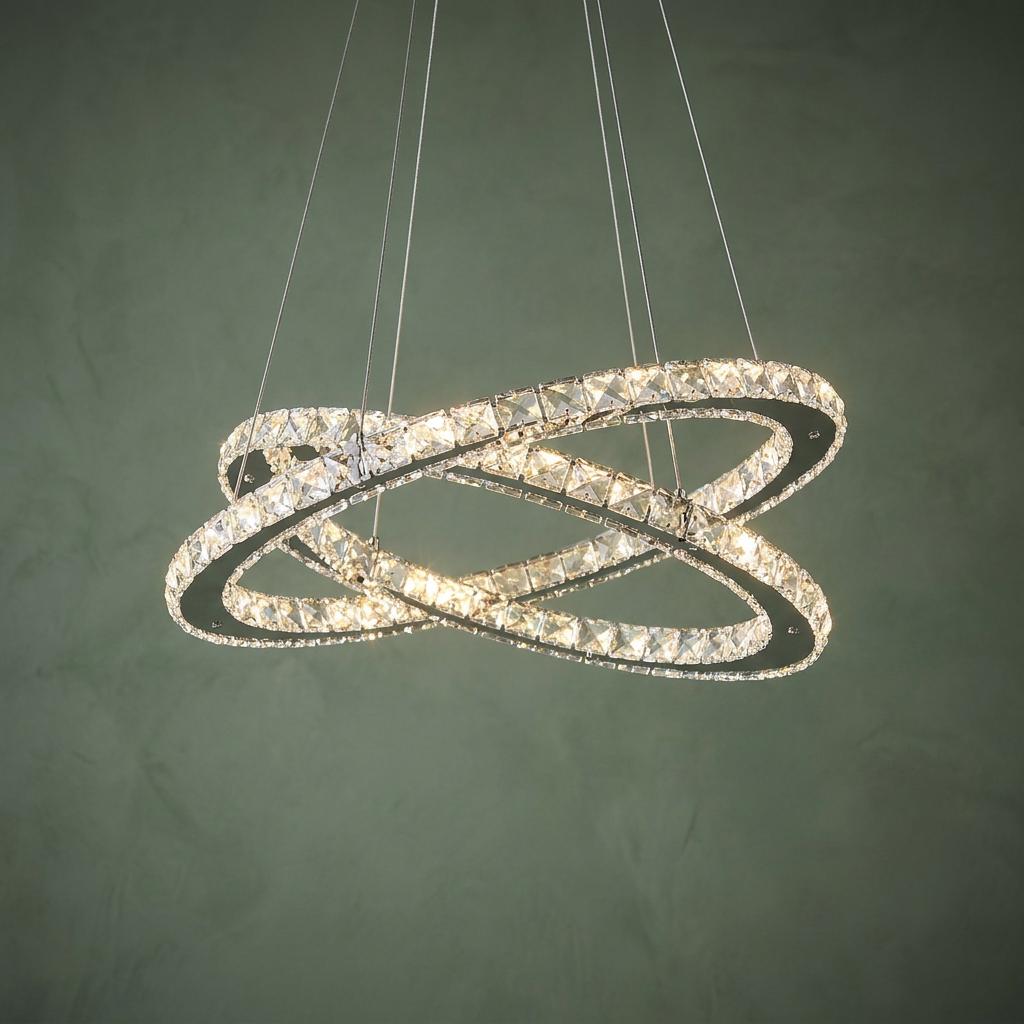 Chrome and glass crystal LED ceiling pendant with two intertwined rings hanging against a textured green wall.