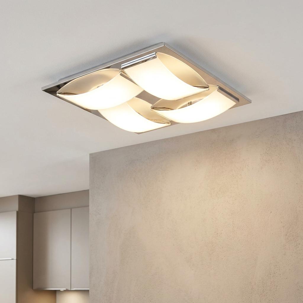 Modern chrome bathroom ceiling light with four curved glowing glass panels mounted on a white ceiling.