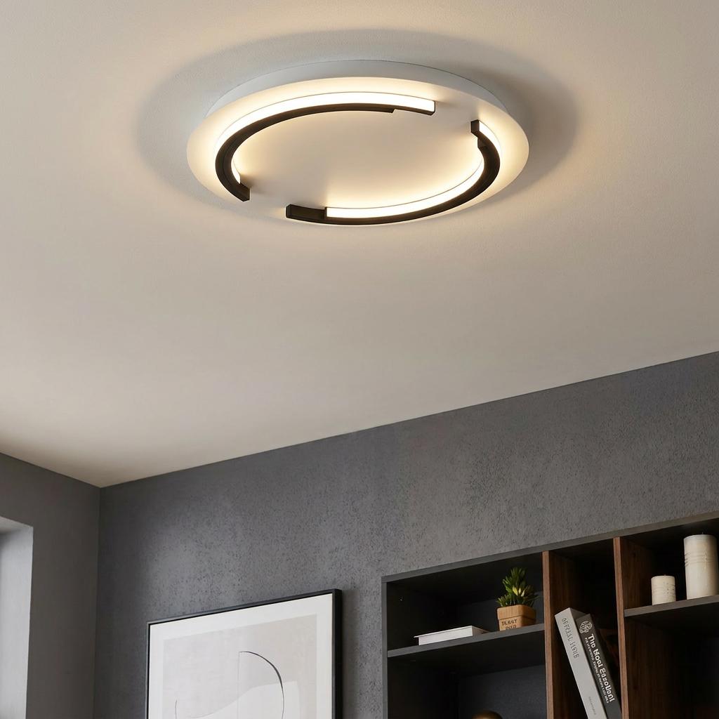 A modern Eglo Zampote round black and white LED flush ceiling light illuminating a contemporary room setting.