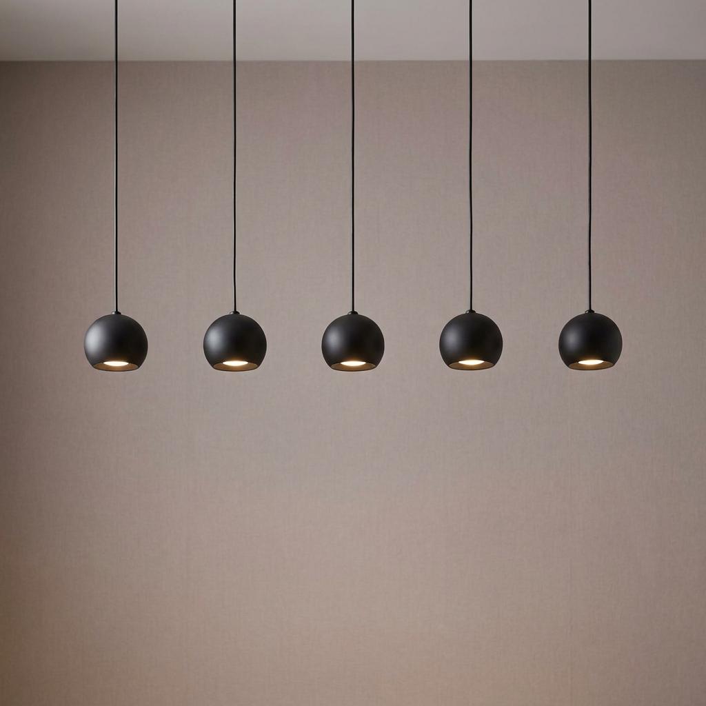 Five matt black spherical pendant lights hanging in a row against a beige wall.
