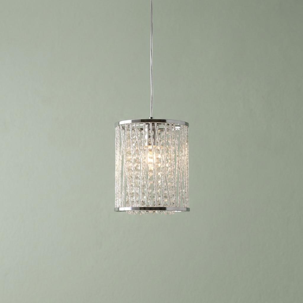 A chrome and crystal cylinder pendant light with glowing beads against a sage green wall.