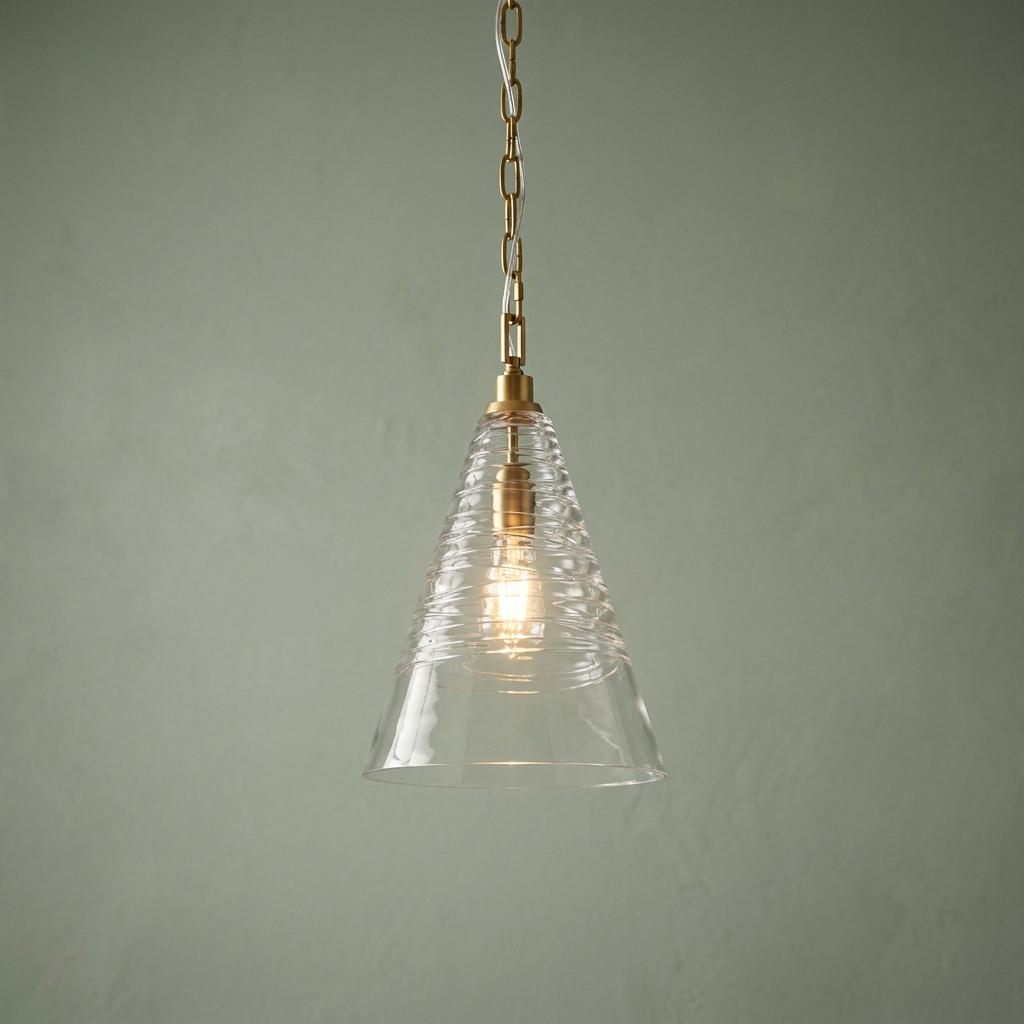 Elmore 1 Light Brass Pendant with a conical ribbed glass shade hanging against a sage green wall.