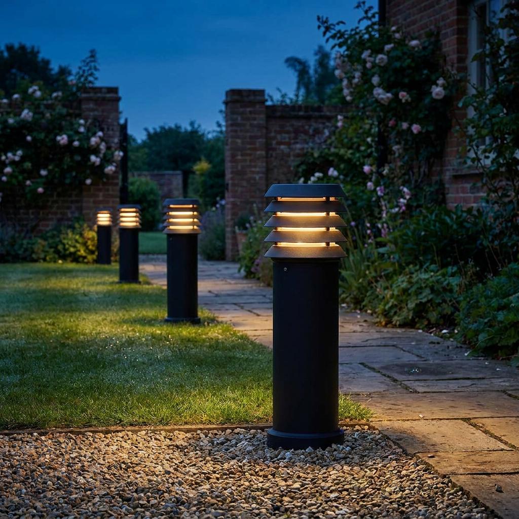 Black tiered bollard lights with warm glows lining a stone garden path at twilight.