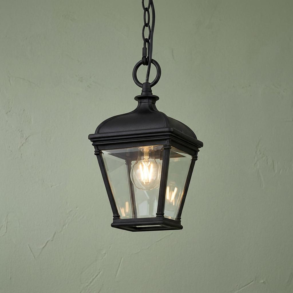 Elstead Bayview 1 light black outdoor chain lantern with clear glass panels, lit against a green textured wall.
