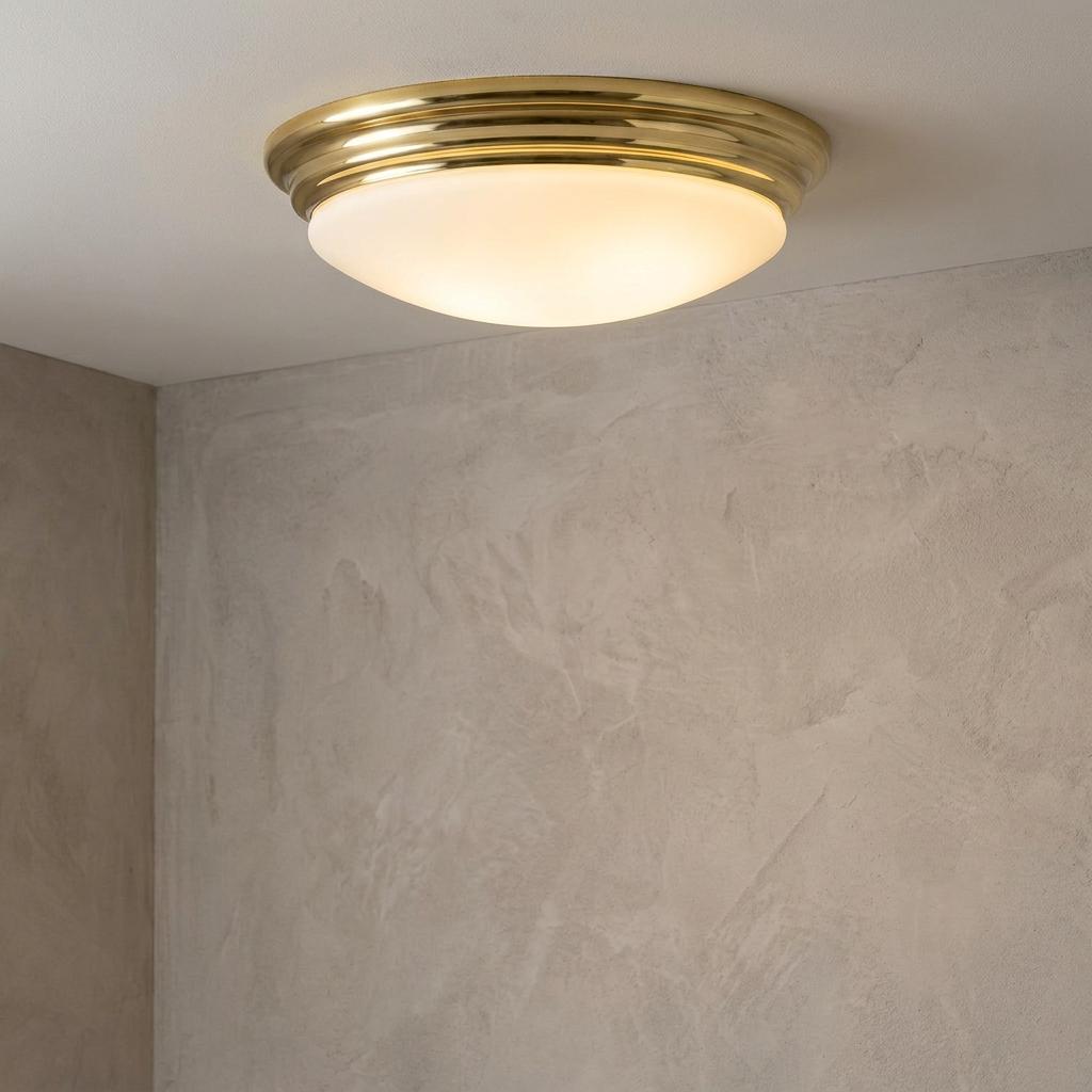Polished brass bathroom flush mount ceiling light with a dome-shaped white glass shade.