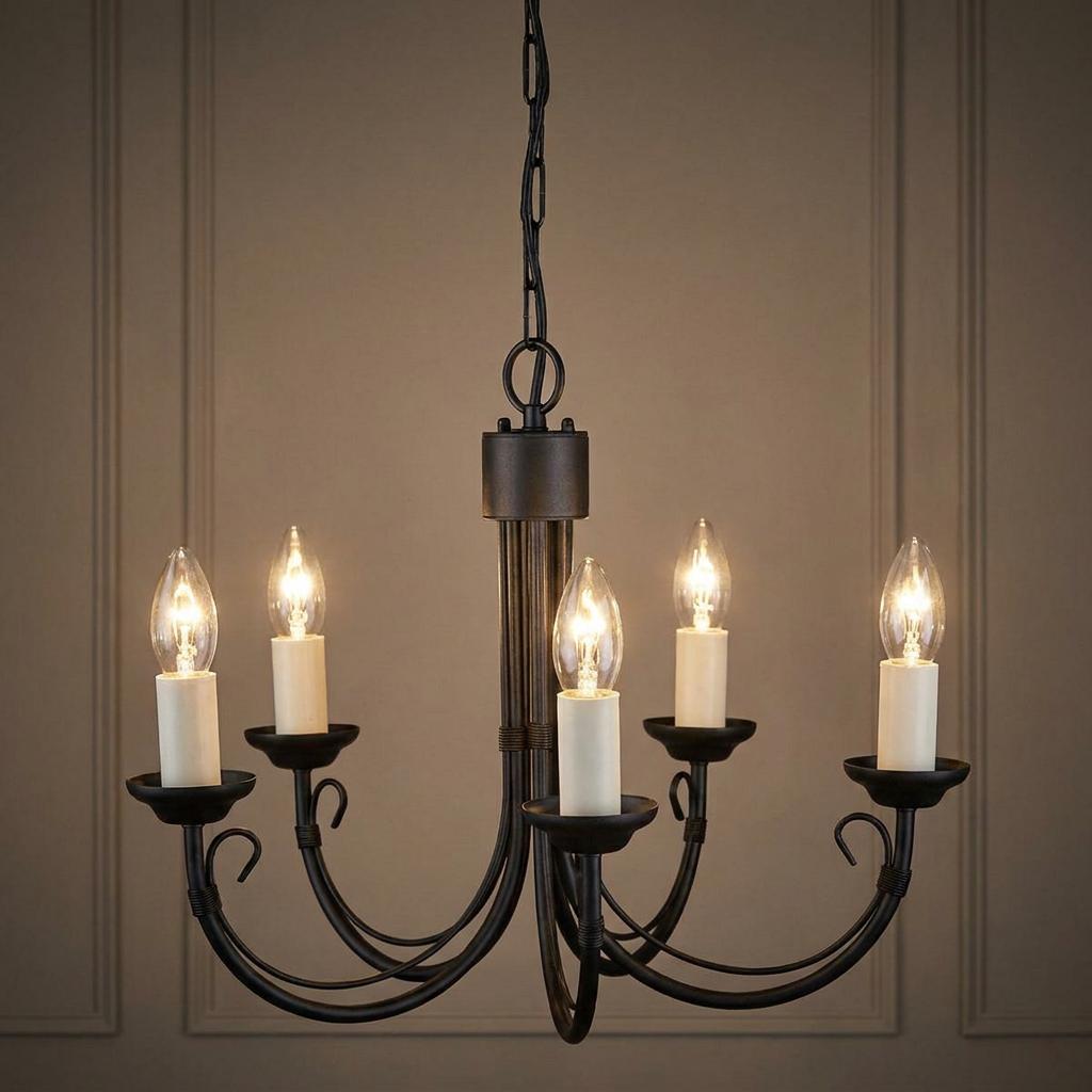 Black five-light chandelier with illuminated candle bulbs hanging against a neutral panelled wall.
