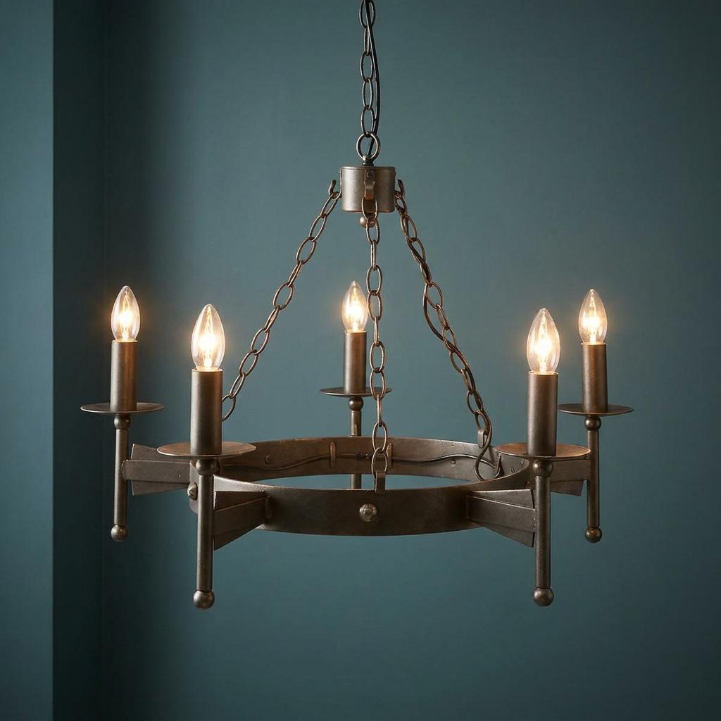 5-light bronze chandelier with medieval-style iron ring and lit candle bulbs against a dark blue wall.