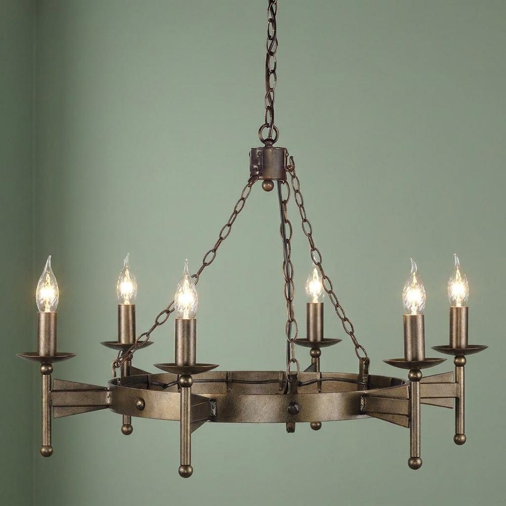 Six-light olde bronze Cromwell chandelier with candle bulbs hanging against a plain green wall.