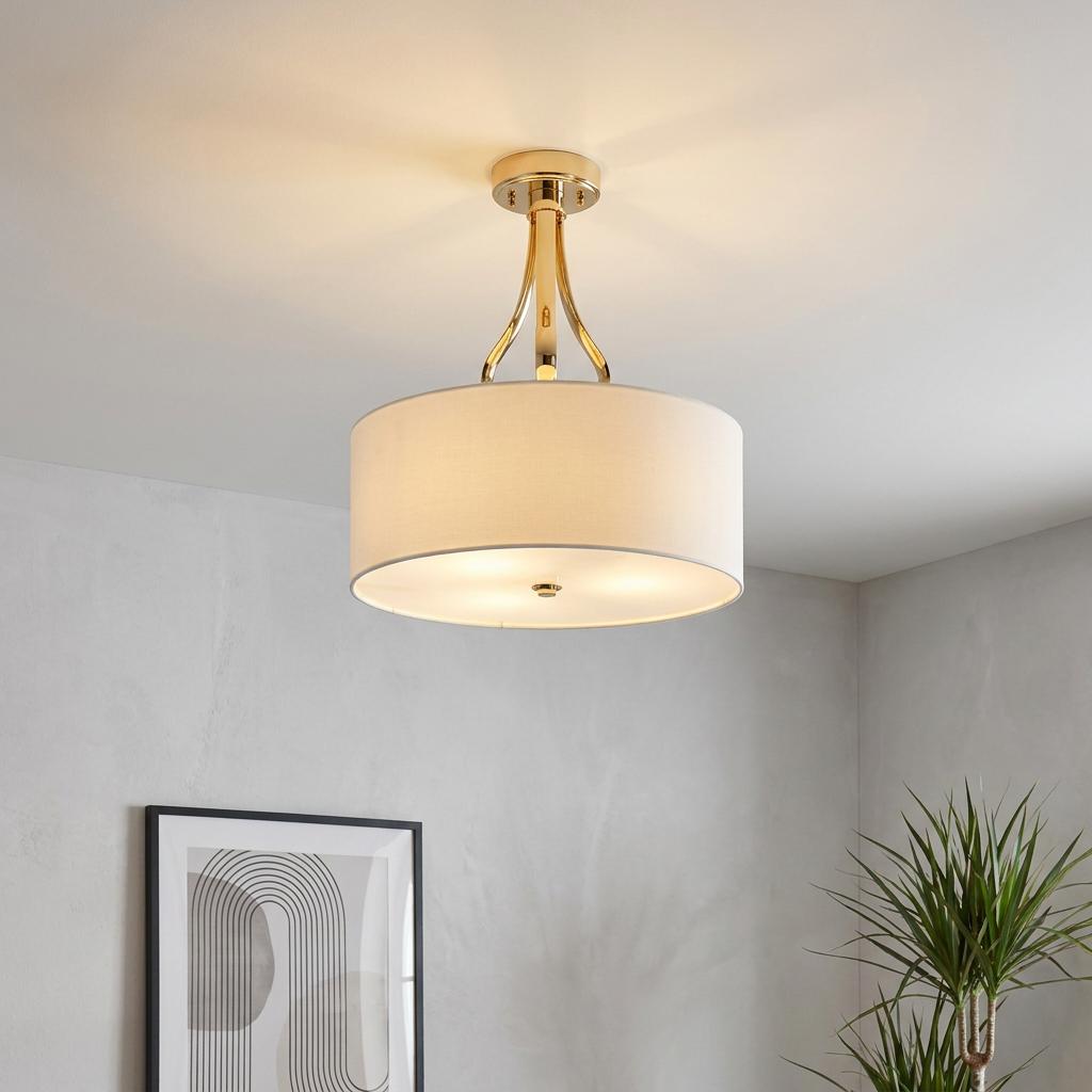 Gold-finished 3-light semi-flush ceiling fixture featuring a white drum fabric shade in a modern interior.