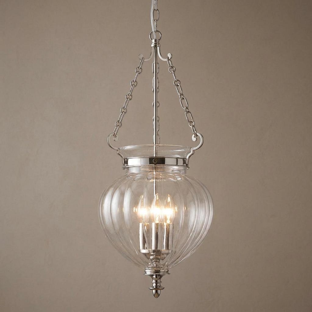 Three-light polished nickel ceiling lantern with clear ribbed glass globe hanging against a neutral wall.