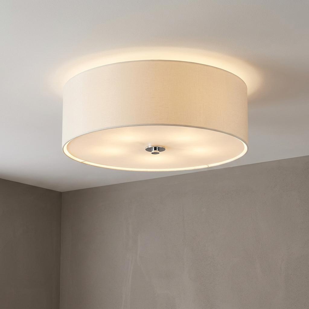Minimalist off-white flush drum ceiling light with a chrome finial casting a warm glow in a neutral room.