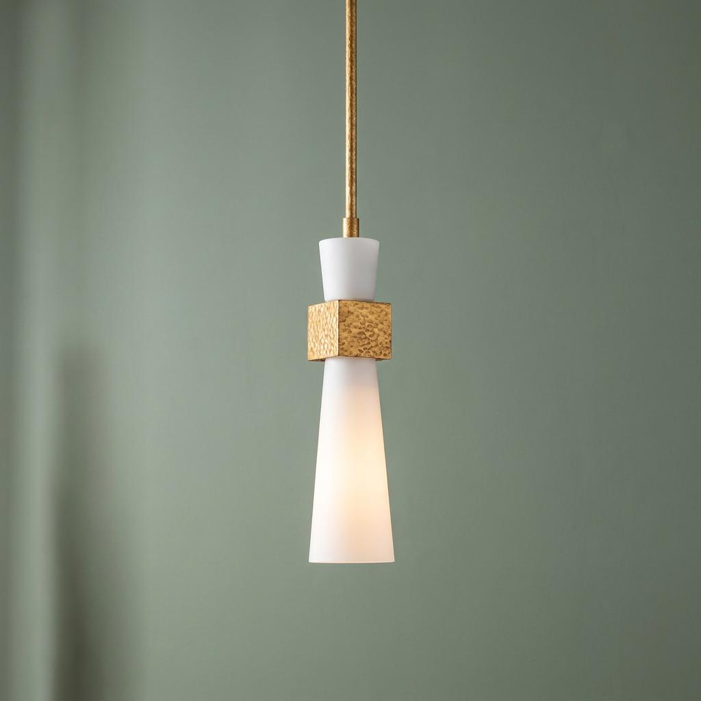 Modern pendant light with white opal glass shades and a hammered gold central block against a sage green wall.
