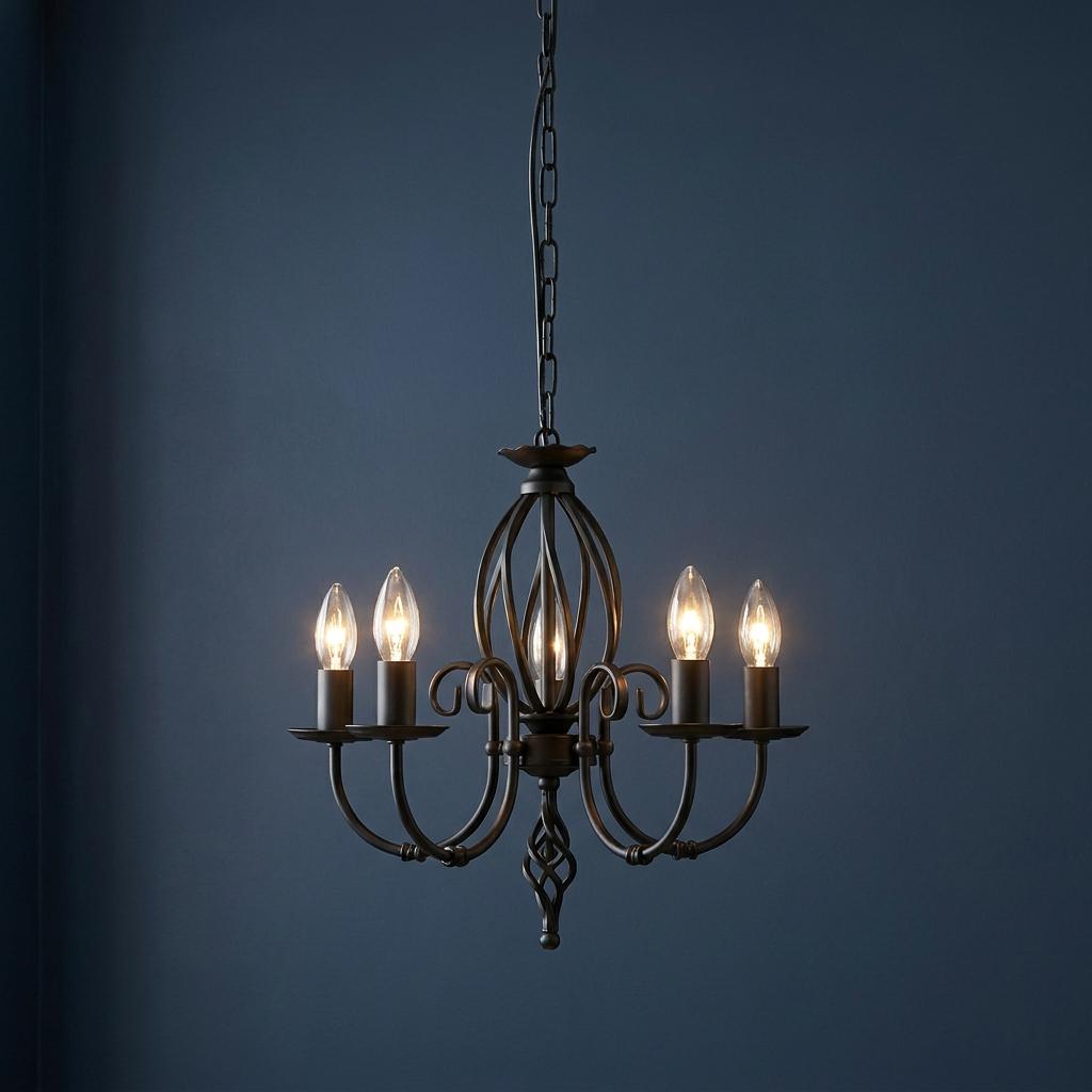 Five-light black wrought iron chandelier with lit candle bulbs and scrollwork against a dark blue wall.