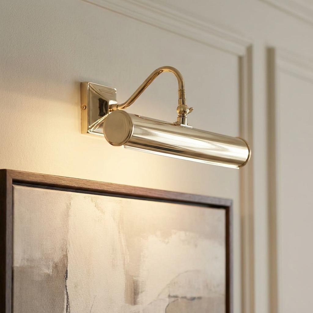 Polished brass Elstead Lighting picture light with a cylindrical head mounted above an abstract painting on a wall.