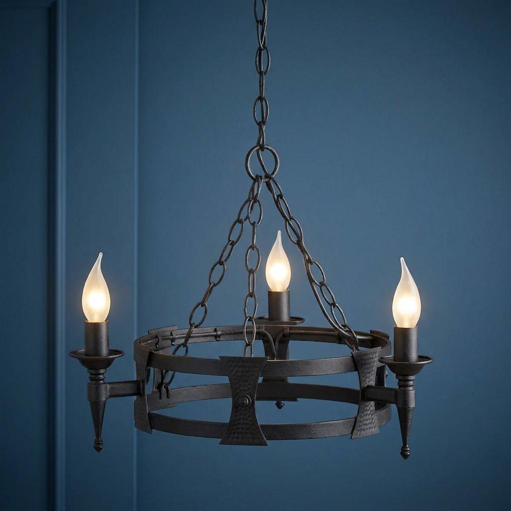 Black 3-light Saxon chandelier with a medieval hoop design and glowing flame-shaped bulbs against a blue wall.