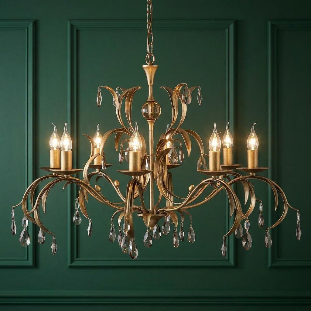Eight-light bronze patina chandelier with leaf-inspired branches and hanging crystals against a green paneled wall.