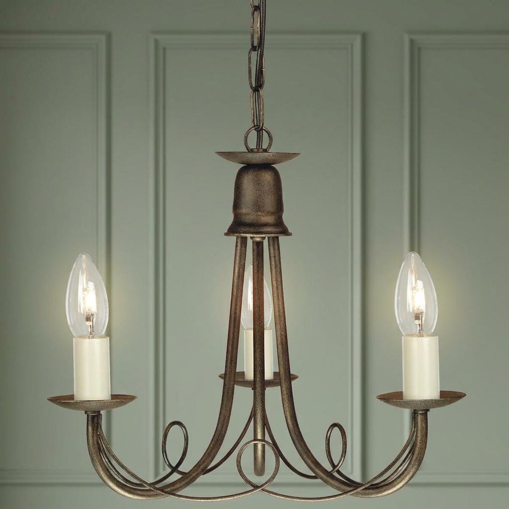 Elstead Minster 3 light chandelier in black and gold finish against a green panelled wall.