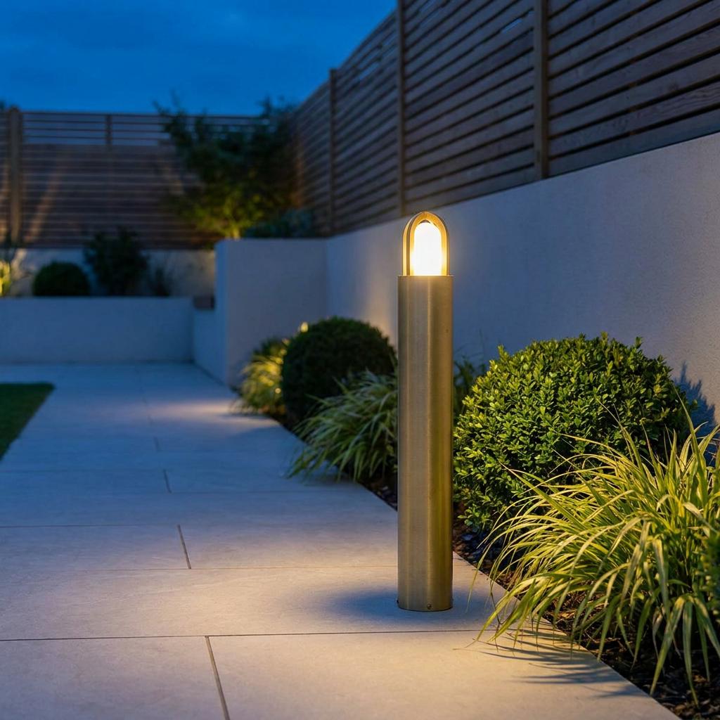 Elstead Paignton brass outdoor bollard light illuminating a stone garden path at dusk.