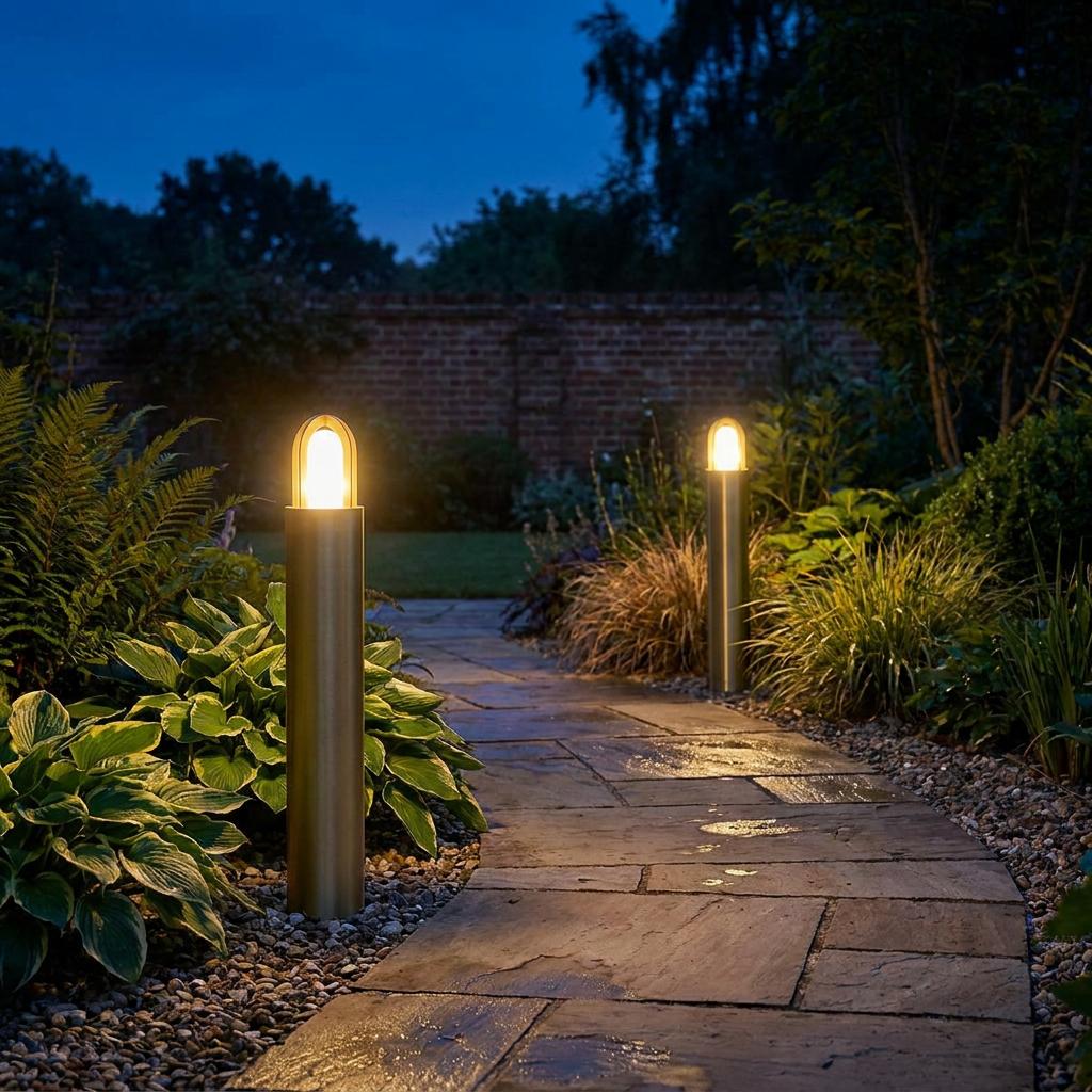 Two brass bollard lights illuminating a stone garden path at dusk among lush green foliage.
