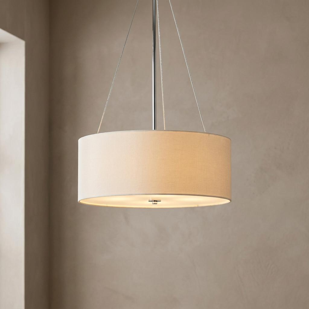 Beige fabric drum pendant light with chrome accents suspended from thin wires in a neutral room.