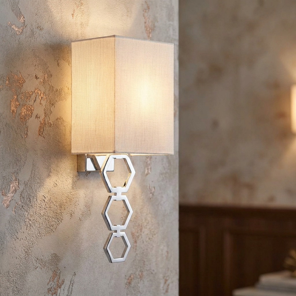 Polished chrome wall light with three hexagonal rings and a cream fabric shade mounted on a textured wall.