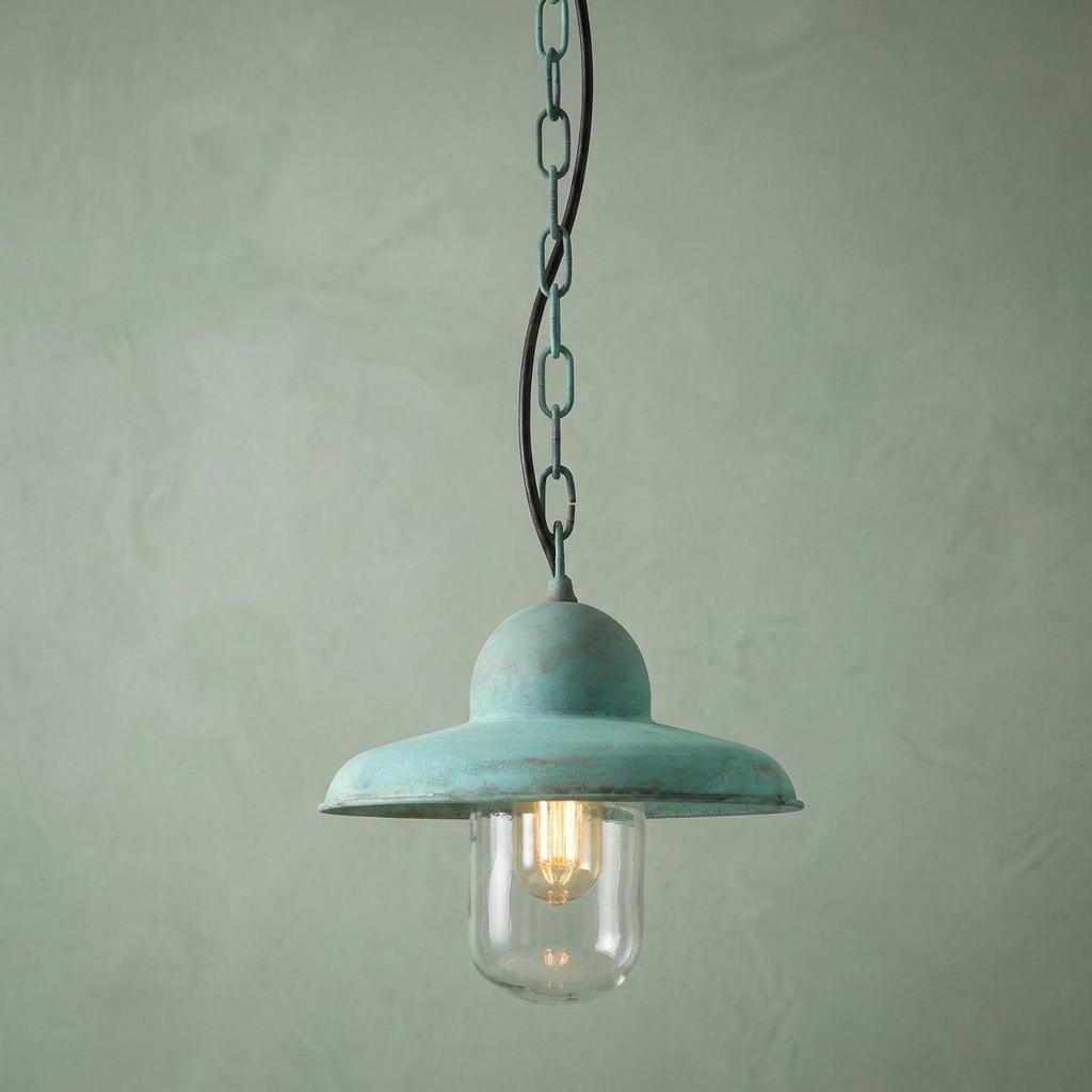 Elstead Somerton outdoor pendant light in a verdigris finish with a clear glass shade against a green wall.