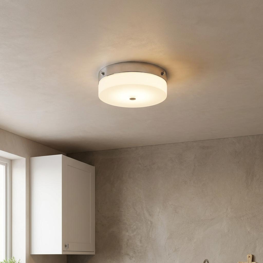 A round opal glass flush ceiling light with a polished chrome trim illuminated in a neutral room.