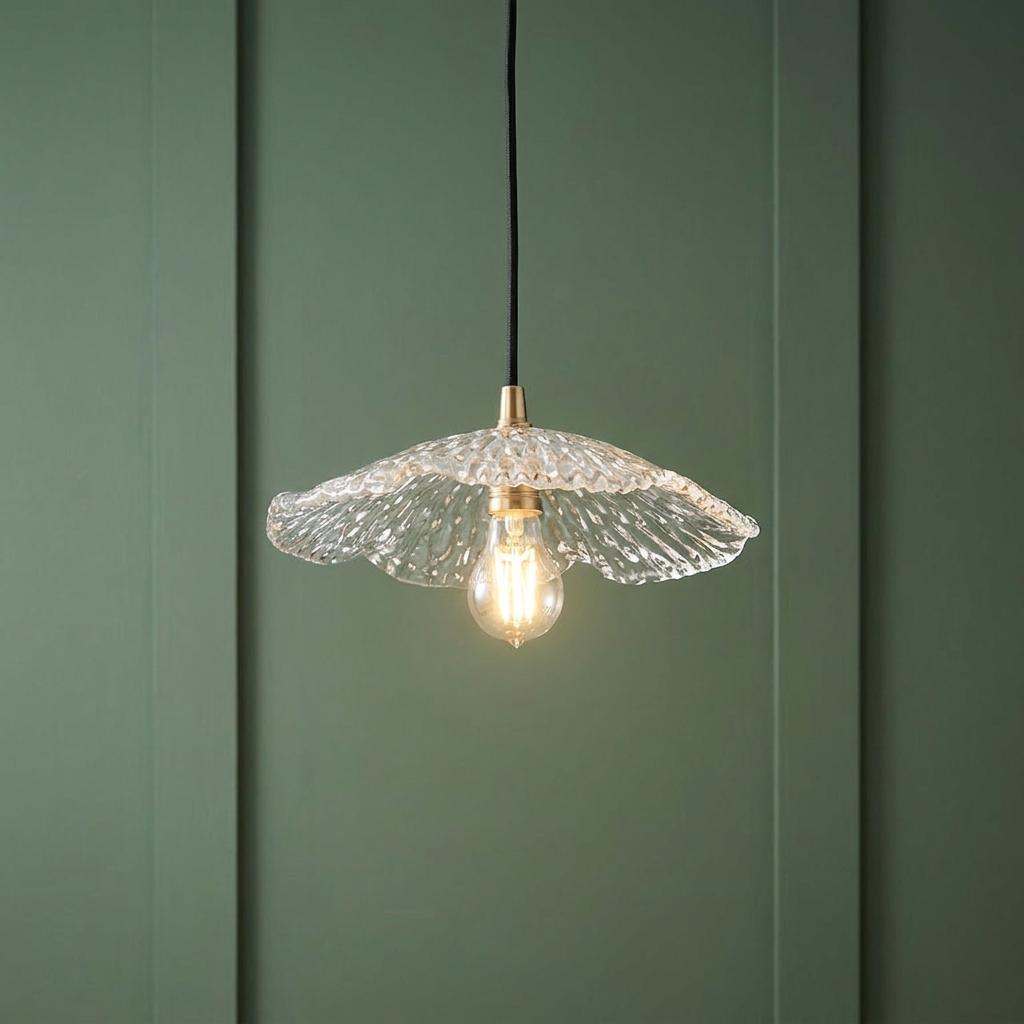 Clear ruffled glass pendant light with brass accents and black cable against a green paneled wall.