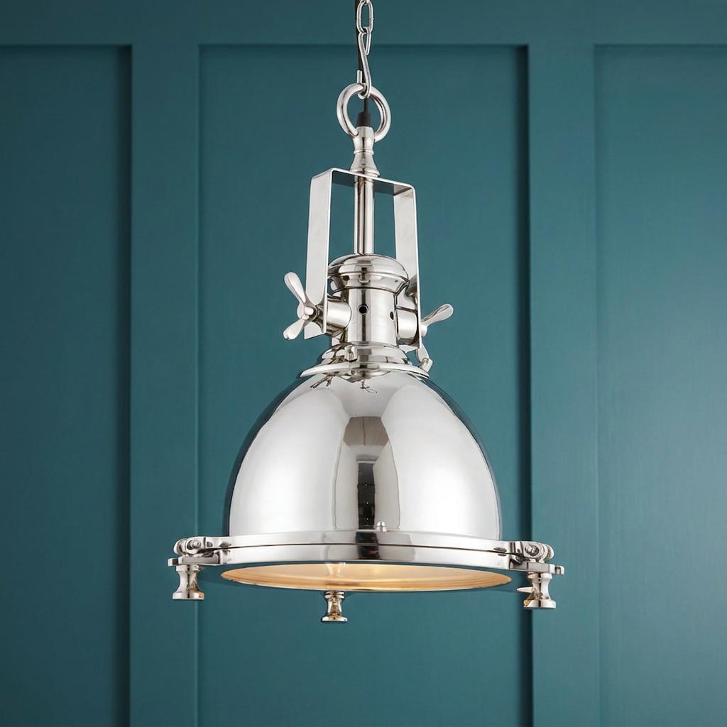 Polished nickel maritime-style dome pendant light with wing nut details against a teal paneled wall.