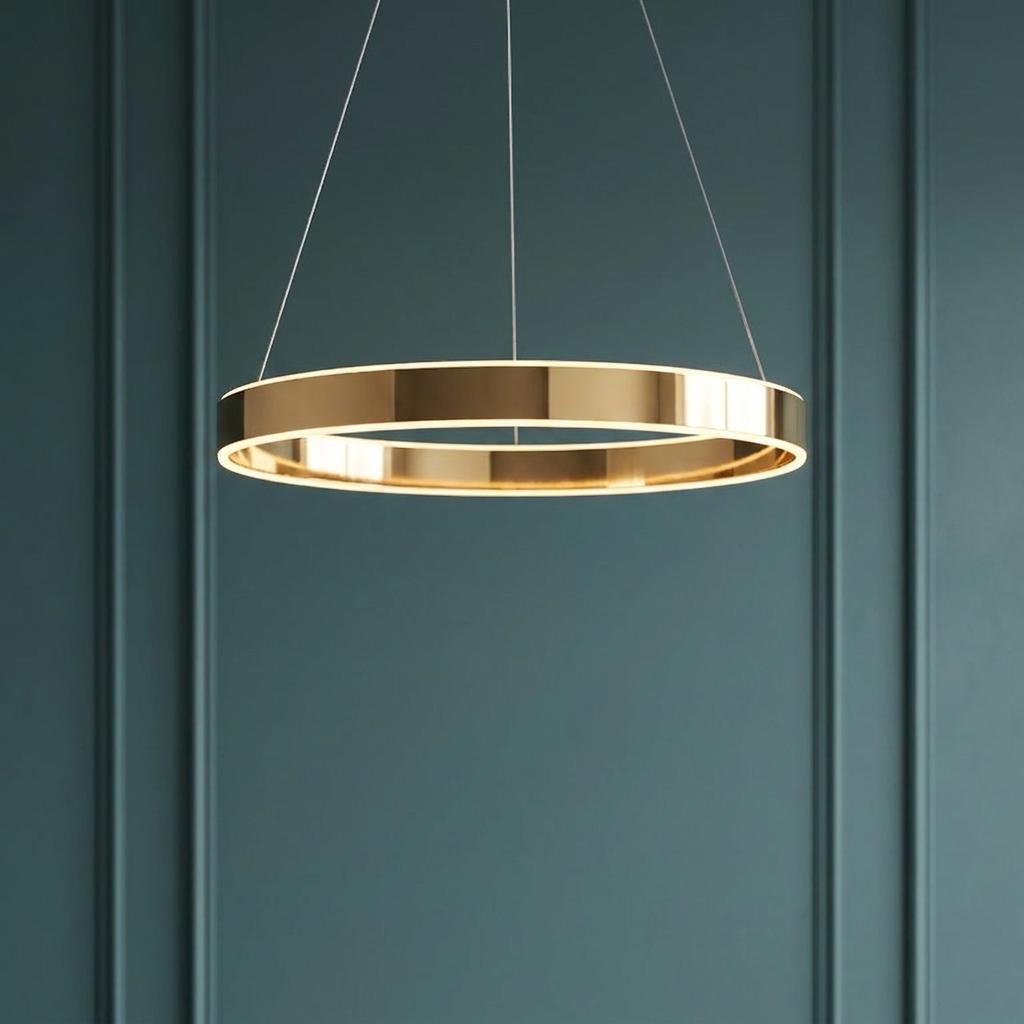 A gold ring LED ceiling pendant with a frosted diffuser emitting warm light against a teal paneled wall.